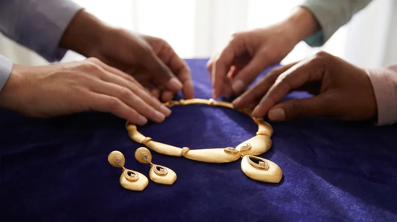 Close view of a gold necklace and earrings laid on dark velvet